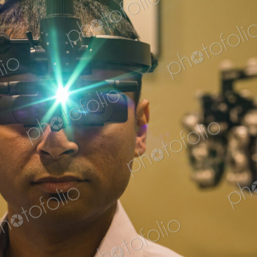 Ophthalmologist wearing a binocular indirect ophthalmoscope for examining eyes.