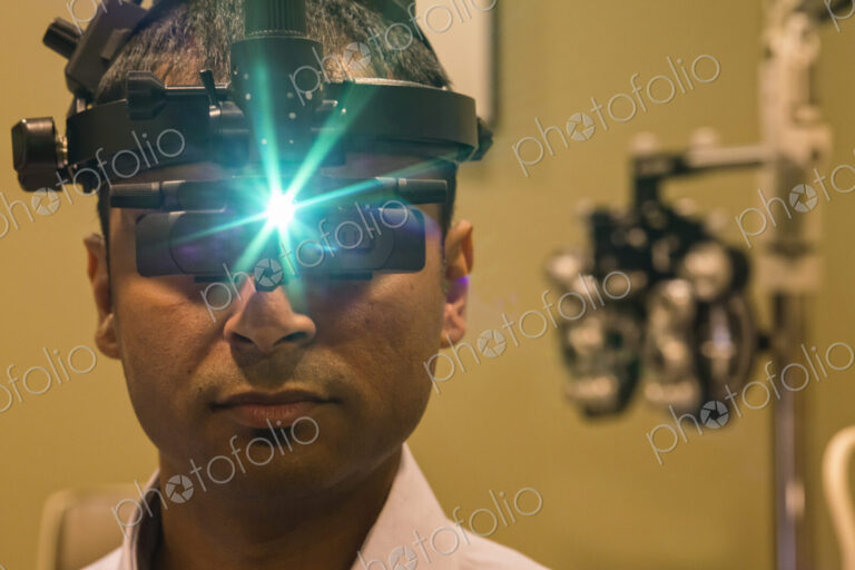 Ophthalmologist wearing a binocular indirect ophthalmoscope for examining eyes.