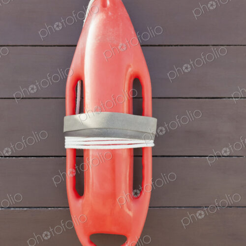 Orange lifeguard buoy, a safety float hanging on a wood wall Orange lifeguard buoy, a safety float hanging on a wood wall