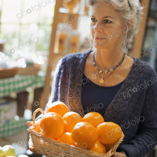 Organic Farmer at Work. A woman carrying a box of large oranges.