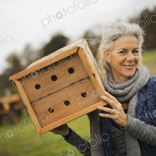 Organic Farmer at Work. A woman holding a bug box, a wooden box with holes for insects… Organic Farmer at Work. A woman holding a bug box, a wooden box with holes for insects…