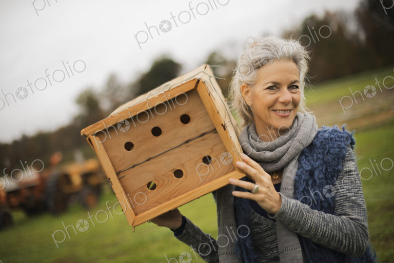 Organic Farmer at Work. A woman holding a bug box, a wooden box with holes for insects…