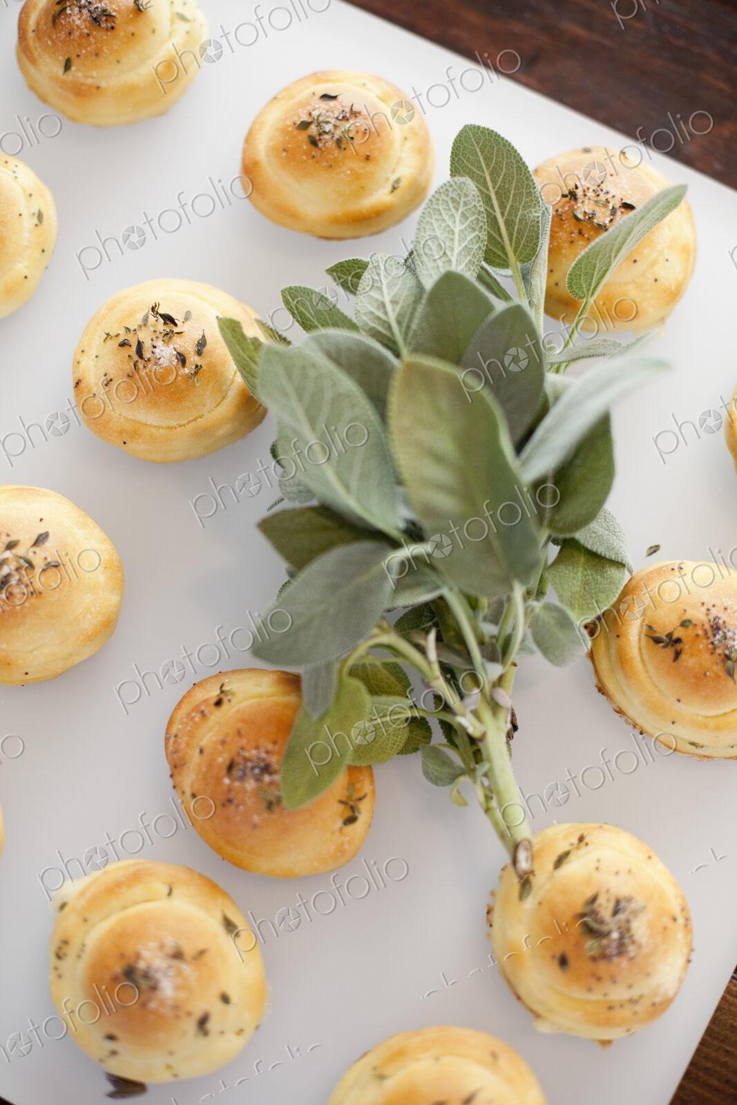 Organic dinner bread rolls on a white board with salt and sage garnish