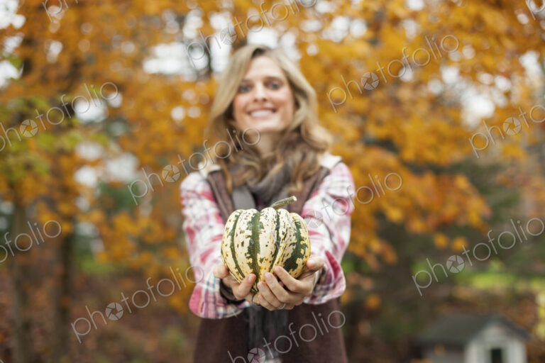 Organic farm. A woman holding a large striped squash vegetable.
