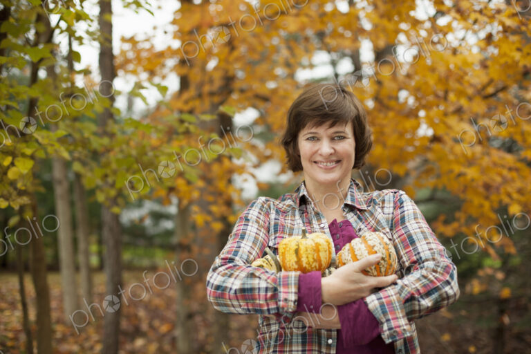 Organic farm. A woman holding an armful of large squash vegetables.