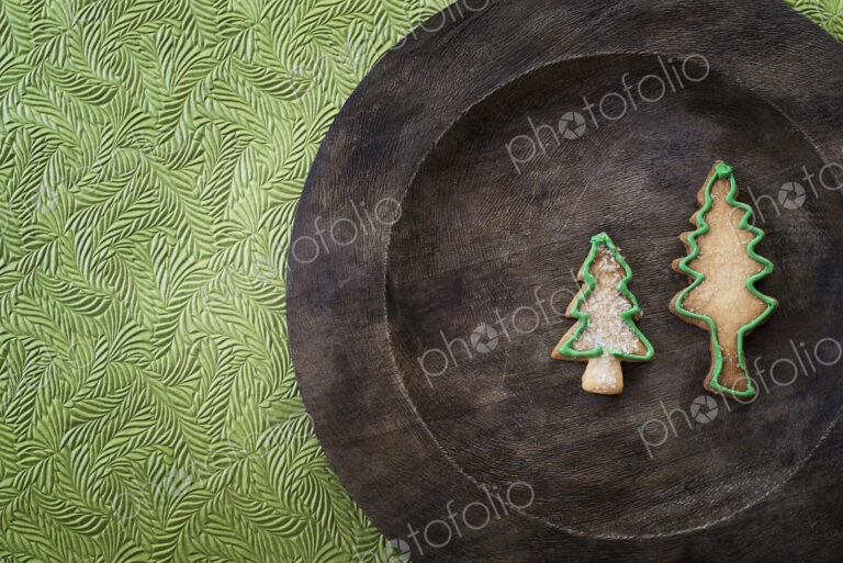 Organic homemade Christmas cookies in the shape of Christmas trees on a round wooden…