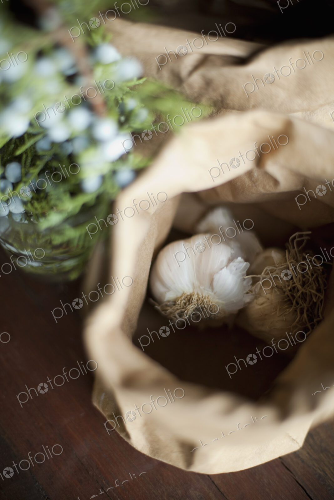 Organic ingredients on a table. Garlic bulbs in a brown paper bag. A herb with with…