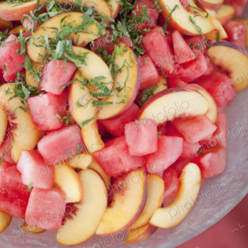 Organic prepared farmstand party food. Summer fruit salad of watermelon, peaches and mint.