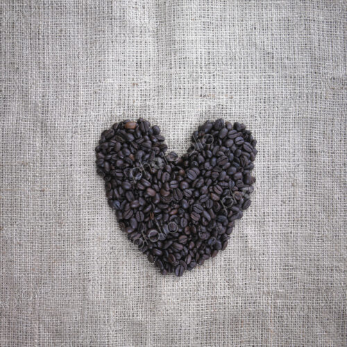 Organic roasted coffee beans in a heart shape on a burlap sack. Organic roasted coffee beans in a heart shape on a burlap sack.