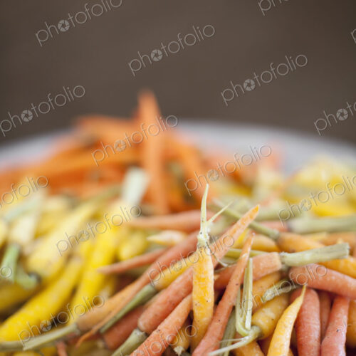 Organic vegetables in a dish. Cooked orange, yellow and pink heritage baby carrots.…