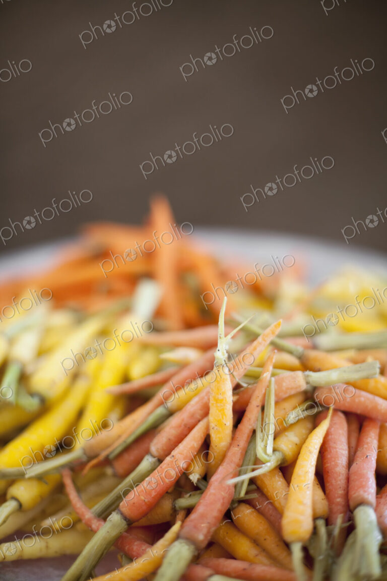 Organic vegetables in a dish. Cooked orange, yellow and pink heritage baby carrots.…