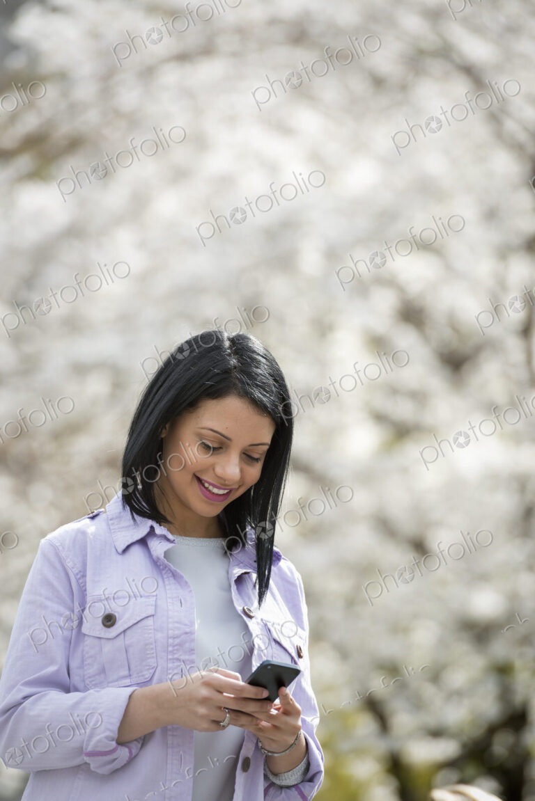 Outdoors in the city in spring time. New York City park. White blossom on the trees. A…