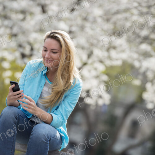Outdoors in the city in spring time. New York City park. White blossom on the trees. A…