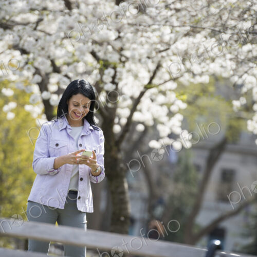 Outdoors in the city in spring time. New York City park. White blossom on the trees. A…