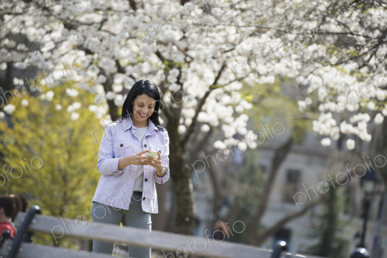 Outdoors in the city in spring time. New York City park. White blossom on the trees. A…