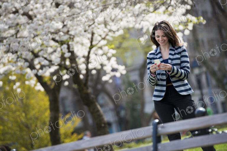 Outdoors in the city in spring time. New York City park. White blossom on the trees. A…
