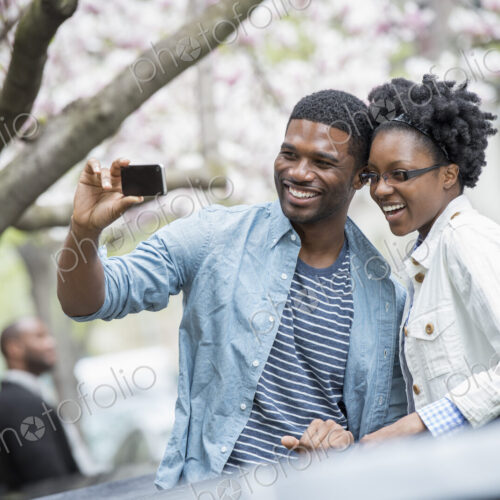 Outdoors in the city in spring. An urban lifestyle. A couple side by side, cheek to…