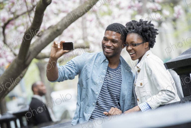 Outdoors in the city in spring. An urban lifestyle. A couple side by side, cheek to…