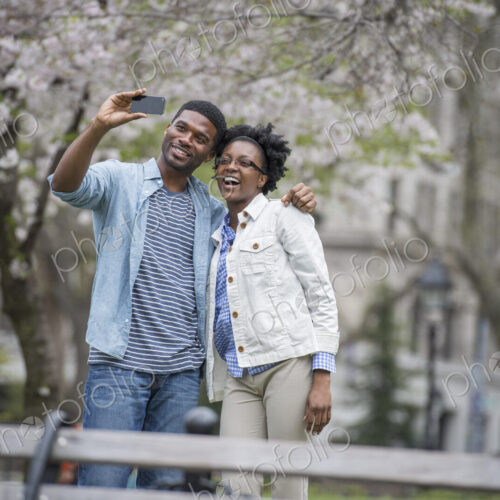 Outdoors in the city in spring. An urban lifestyle. A couple side by side, taking a…