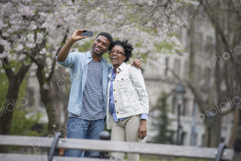 Outdoors in the city in spring. An urban lifestyle. A couple side by side, taking a…