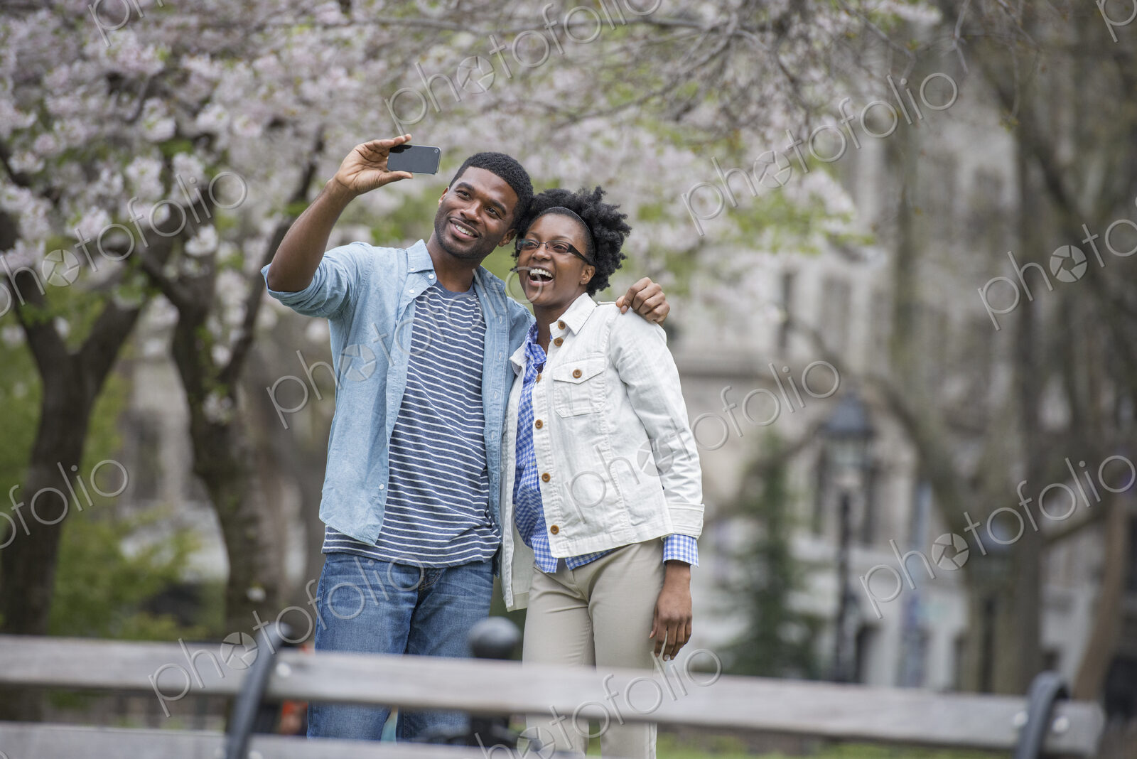 Outdoors in the city in spring. An urban lifestyle. A couple side by side, taking a…
