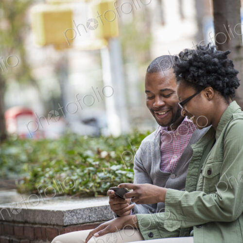 Outdoors in the city in spring. An urban lifestyle. A couple sitting side by side and… Outdoors in the city in spring. An urban lifestyle. A couple sitting side by side and…