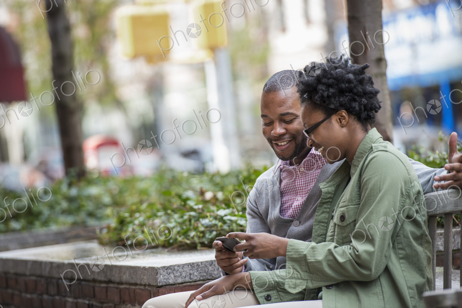 Outdoors in the city in spring. An urban lifestyle. A couple sitting side by side and…