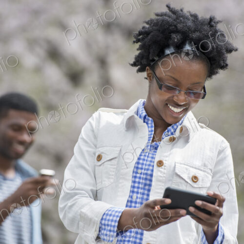 Outdoors in the city in spring. An urban lifestyle. A man and woman both checking…