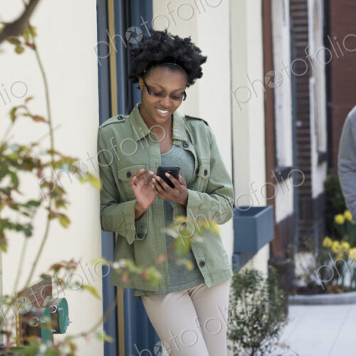 Outdoors in the city in spring. An urban lifestyle. A man approaching a woman who is… Outdoors in the city in spring. An urban lifestyle. A man approaching a woman who is…