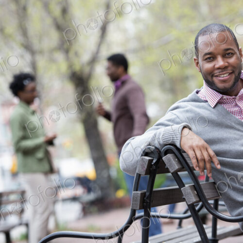 Outdoors in the city in spring. An urban lifestyle. A man seated on a bench, with two… Outdoors in the city in spring. An urban lifestyle. A man seated on a bench, with two…
