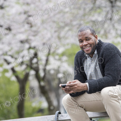 Outdoors in the city in spring. An urban lifestyle. A man sitting on a bench in the…