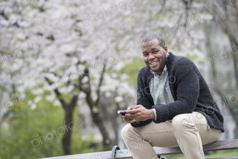 Outdoors in the city in spring. An urban lifestyle. A man sitting on a bench in the…
