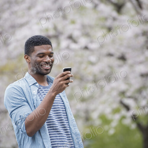 Outdoors in the city in spring. An urban lifestyle. A man standing under a tree laden…