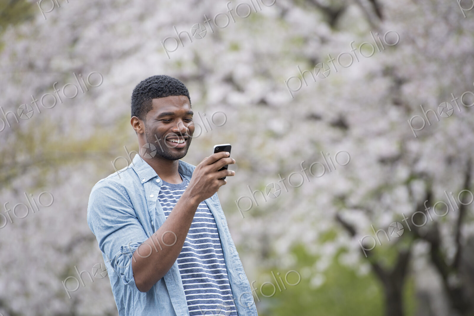 Outdoors in the city in spring. An urban lifestyle. A man standing under a tree laden…