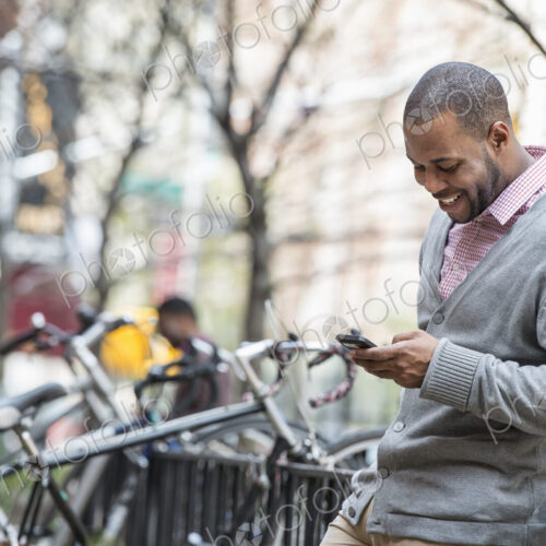 Outdoors in the city in spring. An urban lifestyle. A man using his phone. A group of… Outdoors in the city in spring. An urban lifestyle. A man using his phone. A group of…