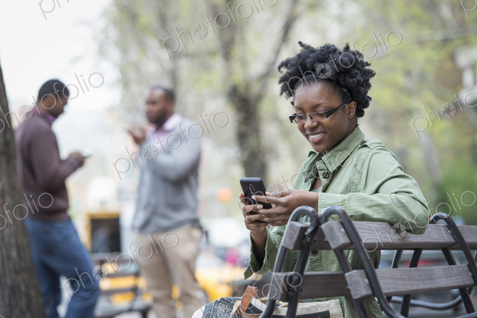 Outdoors in the city in spring. An urban lifestyle. A woman on a bench checking her…