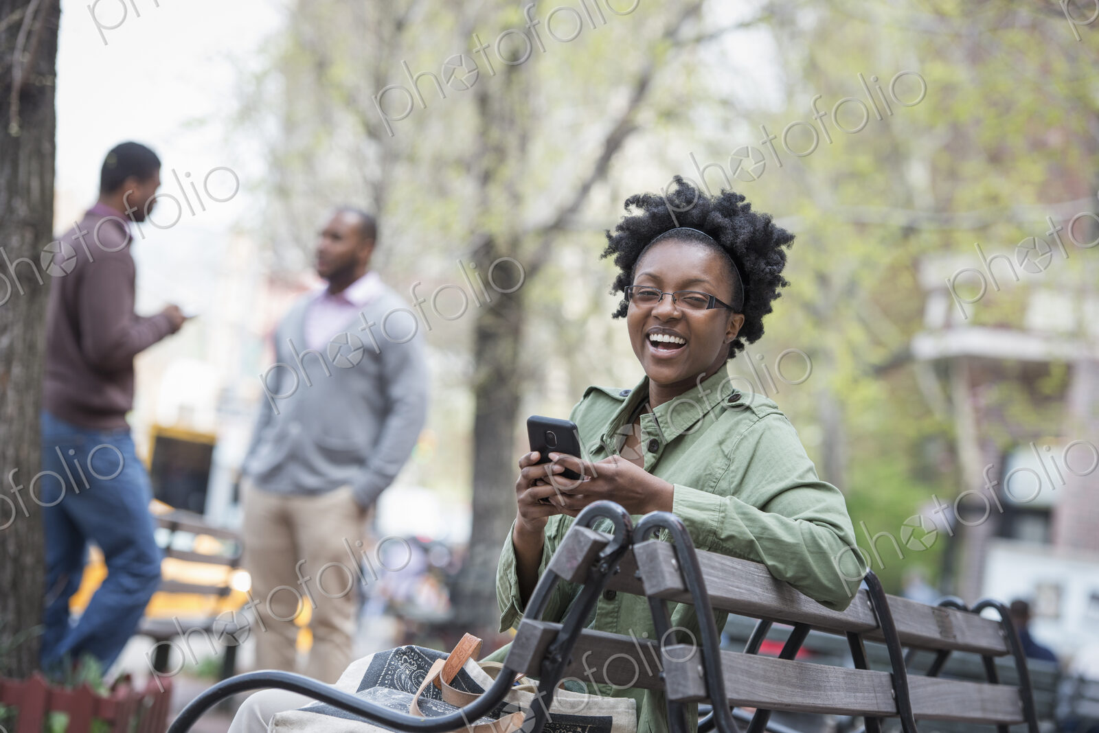 Outdoors in the city in spring. An urban lifestyle. A woman on a bench checking her…