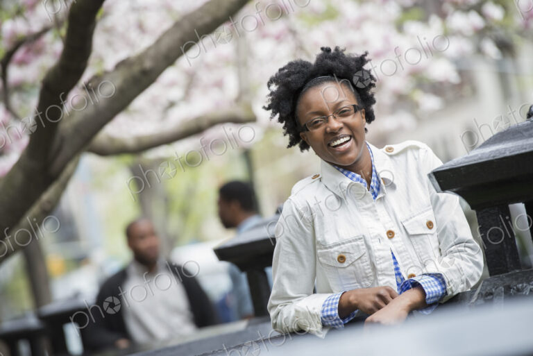 Outdoors in the city in spring. An urban lifestyle. A woman seated at a table with two…