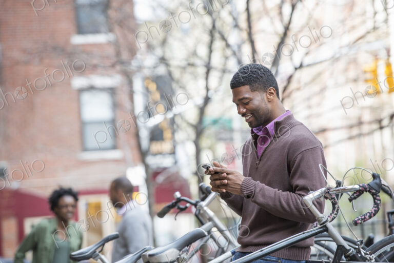 Outdoors in the city in spring. An urban lifestyle. A young man checking his phone and…