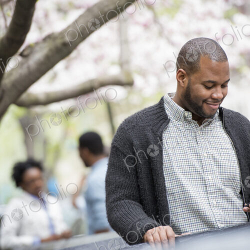 Outdoors in the city in spring. An urban lifestyle. A young man checking his phone and… Outdoors in the city in spring. An urban lifestyle. A young man checking his phone and…