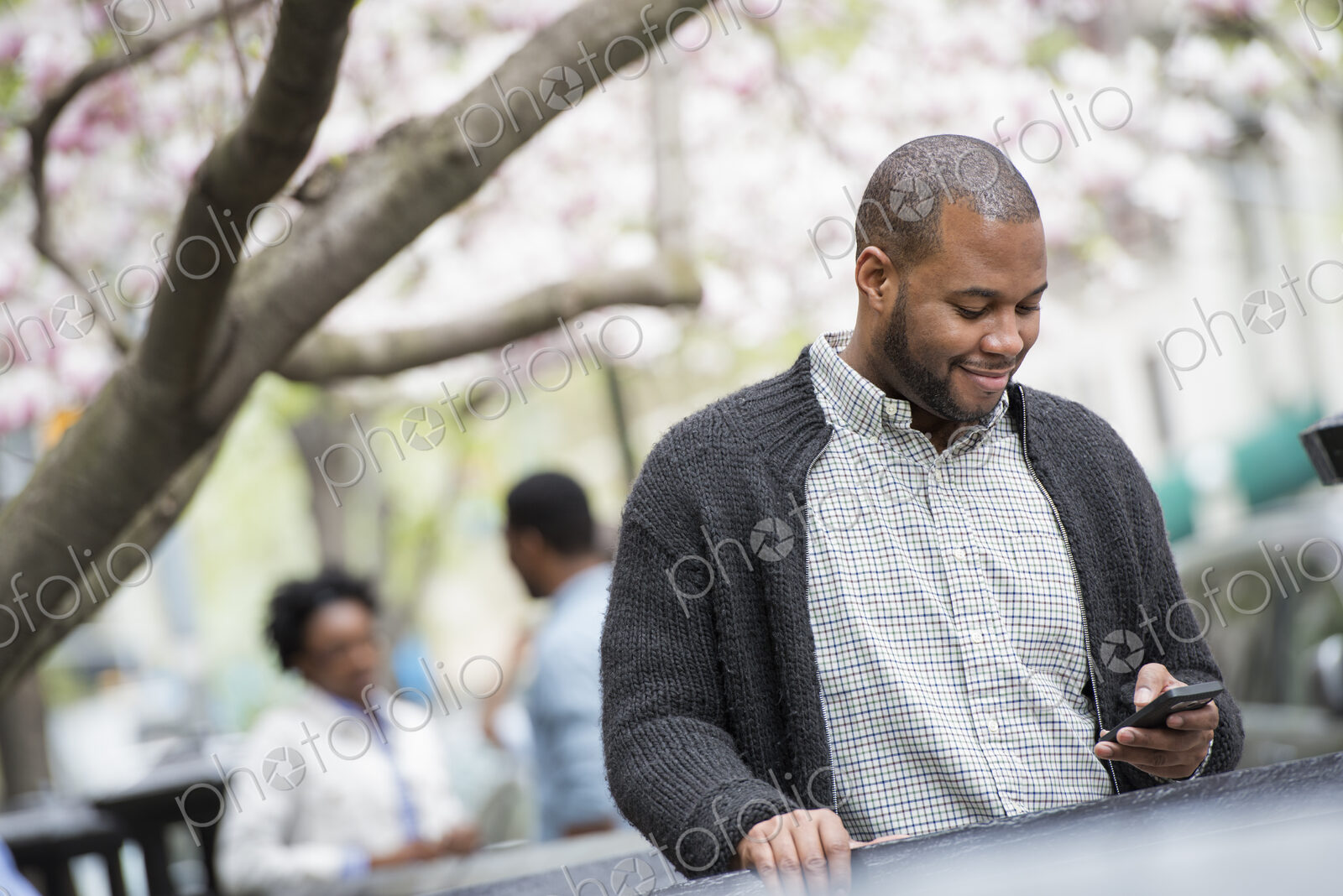 Outdoors in the city in spring. An urban lifestyle. A young man checking his phone and…
