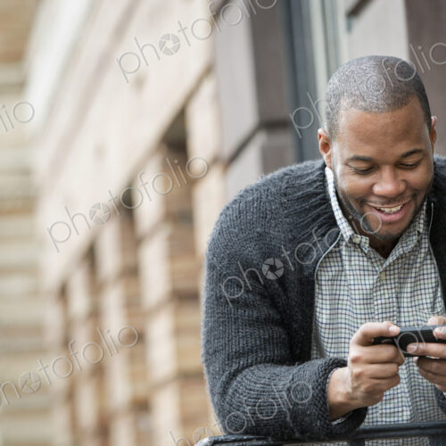 Outdoors in the city in spring. An urban lifestyle. A young man checking his phone and… Outdoors in the city in spring. An urban lifestyle. A young man checking his phone and…