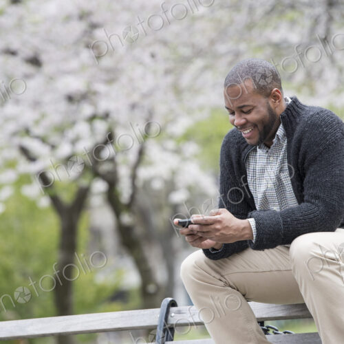 Outdoors in the city in spring. An urban lifestyle. A young man checking his phone and…