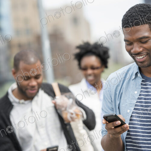 Outdoors in the city in spring. An urban lifestyle. A young man checking his phone and…