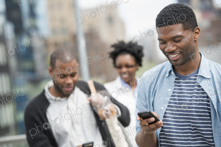 Outdoors in the city in spring. An urban lifestyle. A young man checking his phone and…