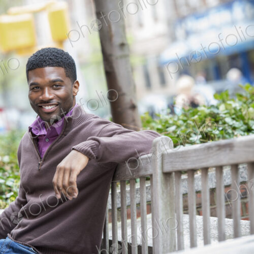 Outdoors in the city in spring. An urban lifestyle. A young man seated on a bench. Outdoors in the city in spring. An urban lifestyle. A young man seated on a bench.