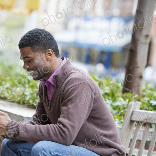 Outdoors in the city in spring. An urban lifestyle. A young man sitting on a bench,… Outdoors in the city in spring. An urban lifestyle. A young man sitting on a bench,…