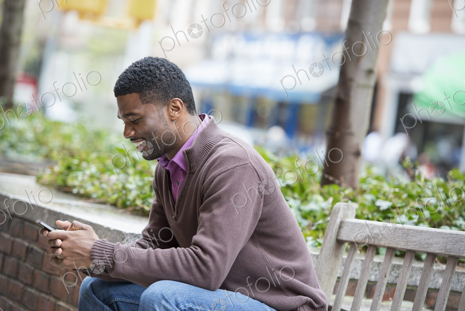 Outdoors in the city in spring. An urban lifestyle. A young man sitting on a bench,…