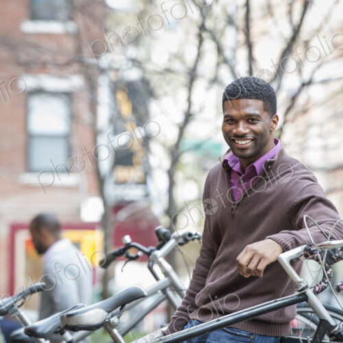 Outdoors in the city in spring. An urban lifestyle. A young man smiling at the camera.…