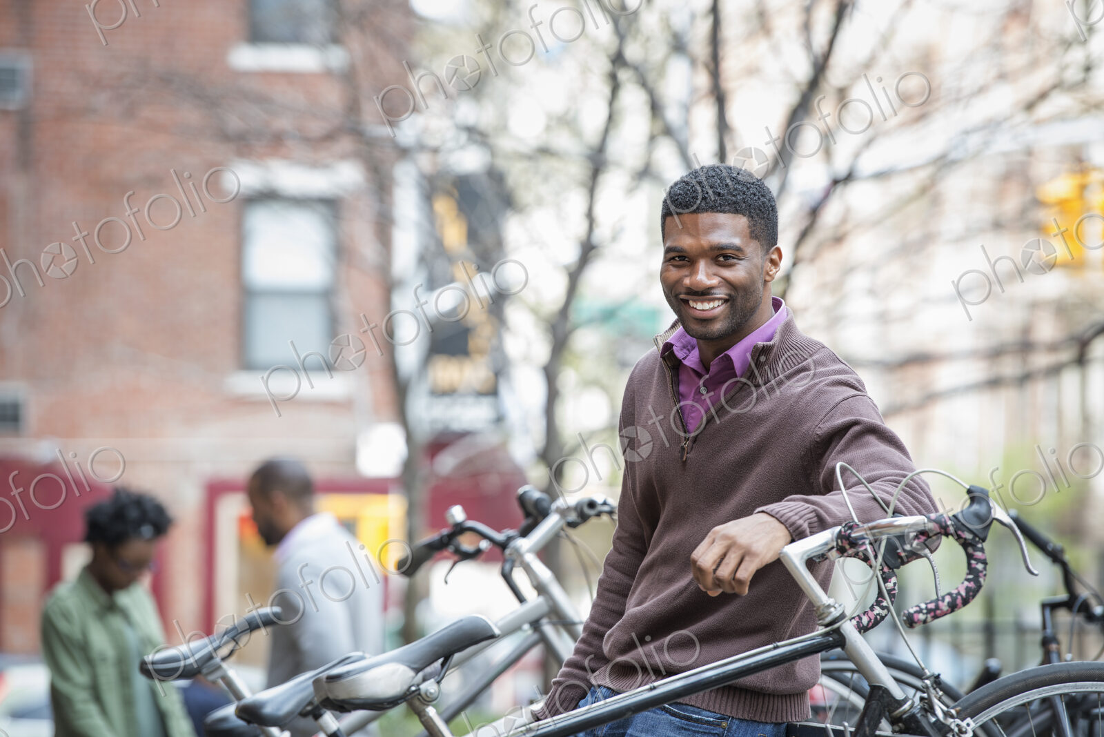 Outdoors in the city in spring. An urban lifestyle. A young man smiling at the camera.…